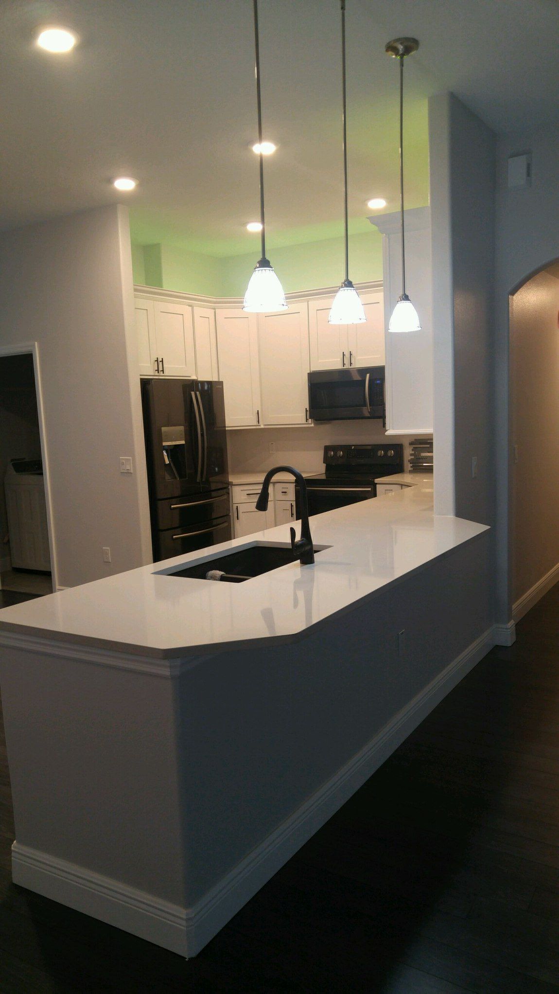 Kitchen with white cabinets, island sink, pendant lights, and dark countertops in an open-plan home.