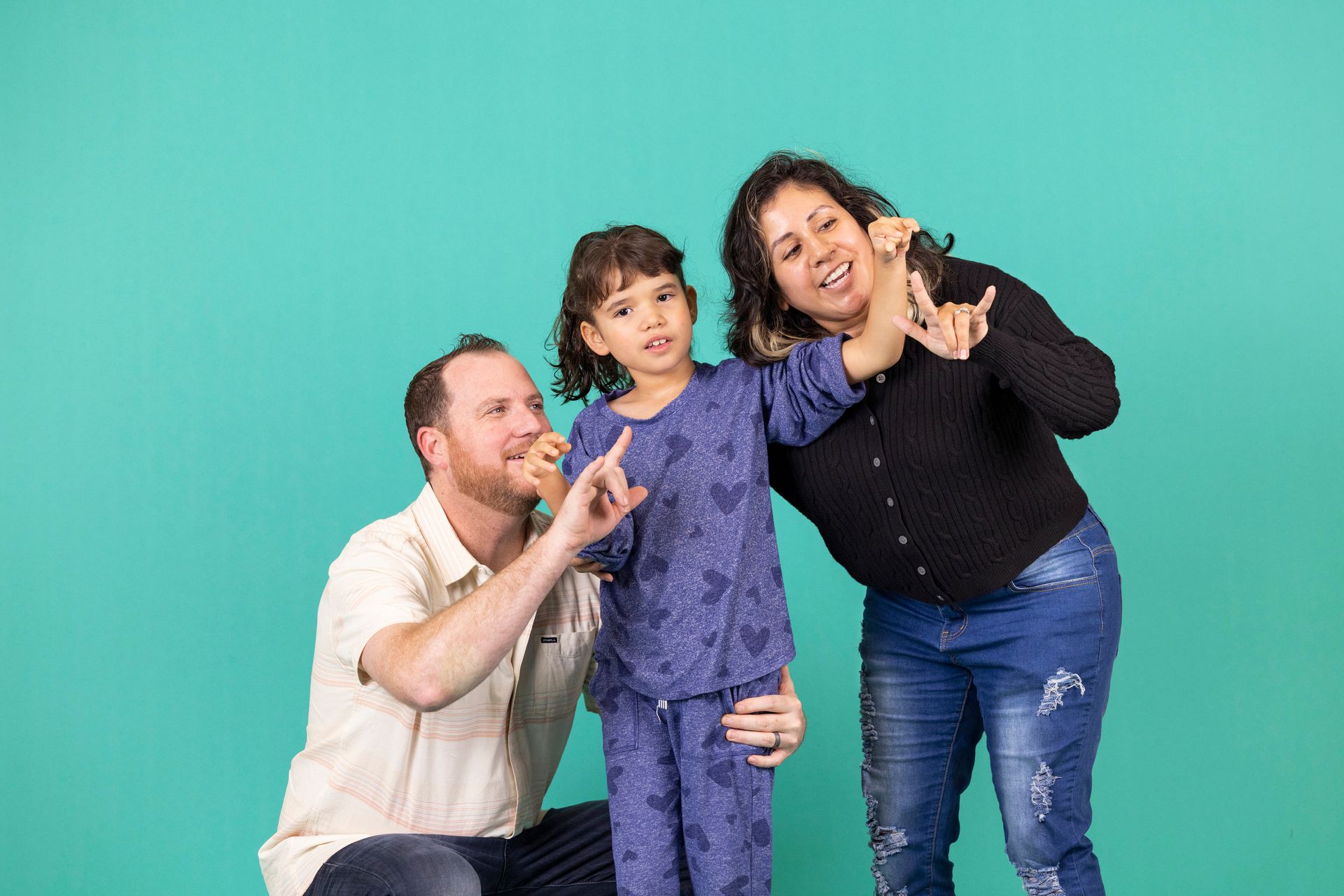 Three people smiling and posing together against a teal background