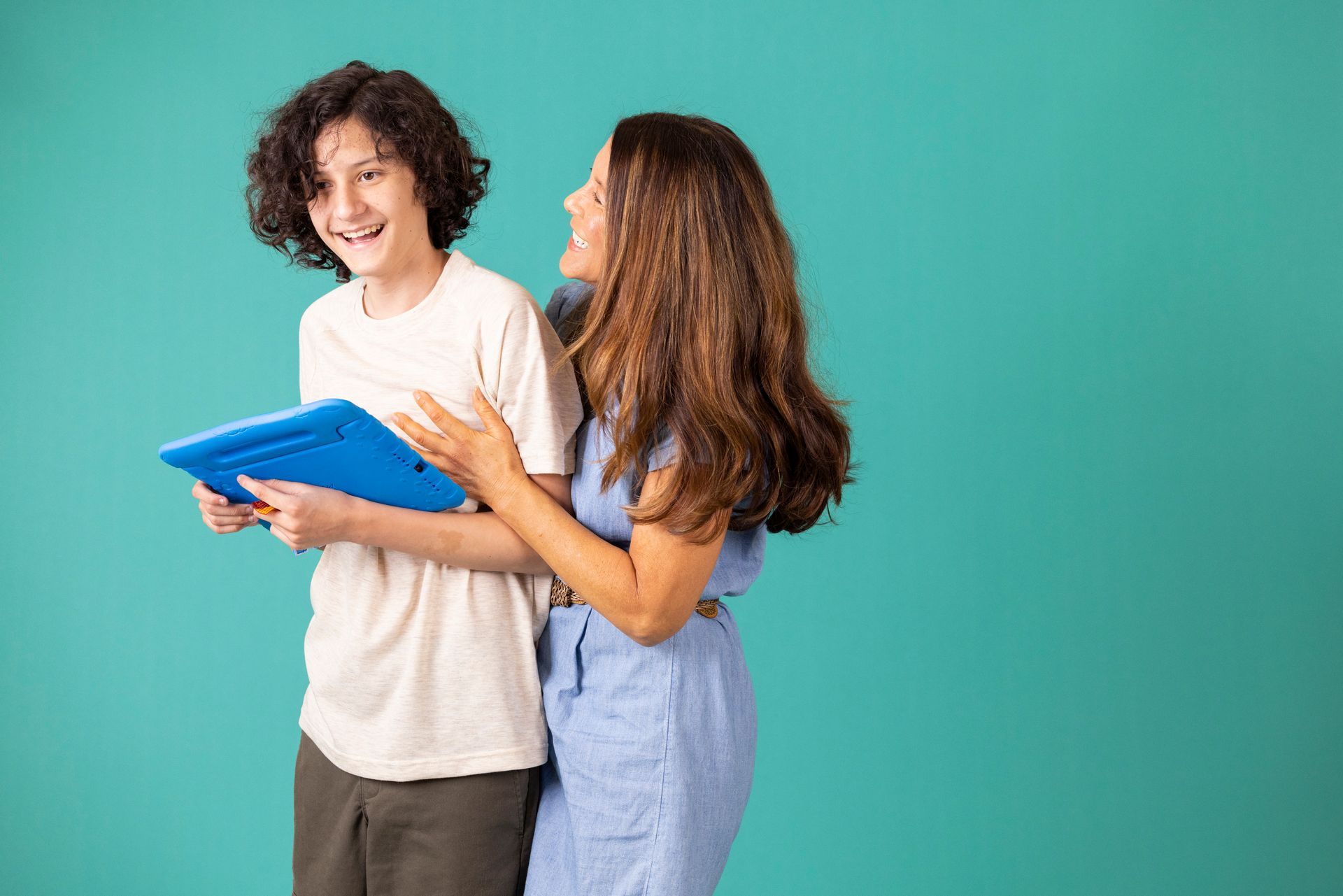 Two people smiling and looking at a blue clipboard against a teal background