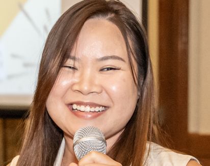 Smiling person speaking into a microphone indoors
