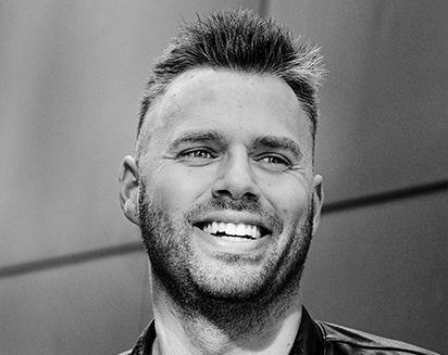 Smiling man with short spiky hair and beard in black-and-white portrait