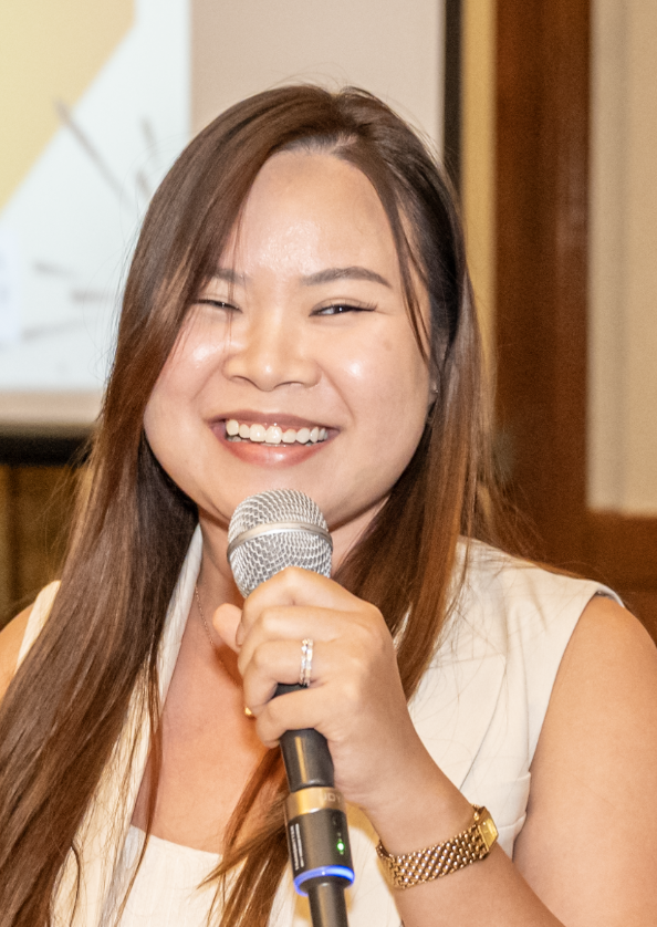 Woman smiling and holding a microphone at an indoor event