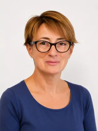 Ritratto di una persona con occhiali e maglietta blu su sfondo chiaro.