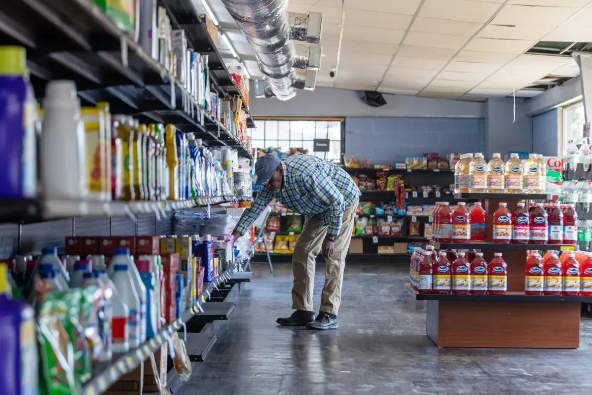 A man is standing in a grocery store looking at a shelf.