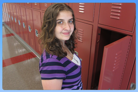 Teenager by red lockers, opening locker door; purple striped shirt.