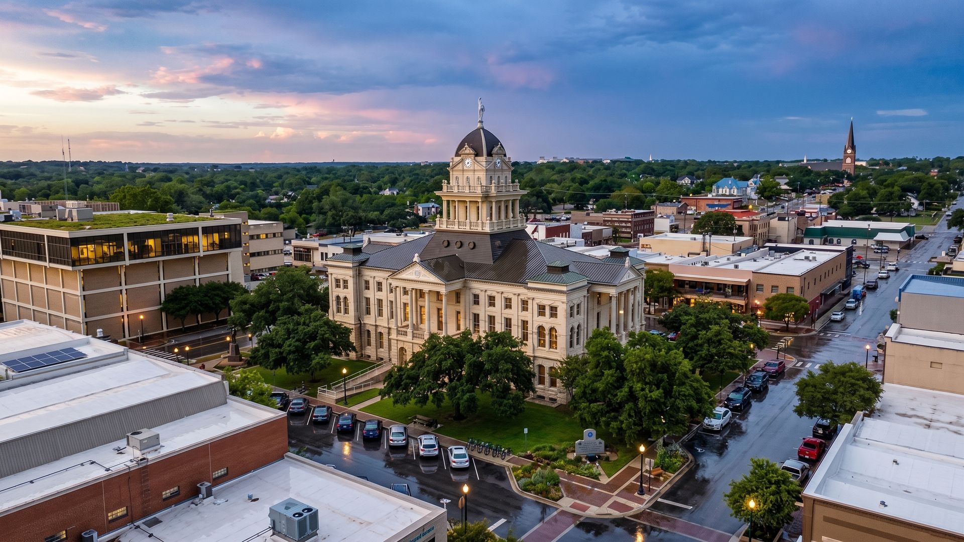 Historic downtown with a domed courthouse at sunset, tree-lined streets, and low-rise buildings.