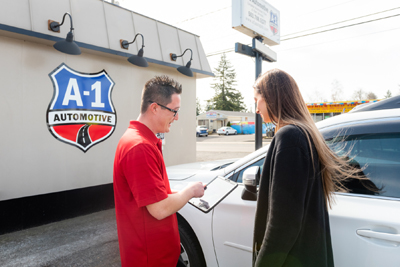 A man is talking to a woman in front of a building that says a-1 automotive