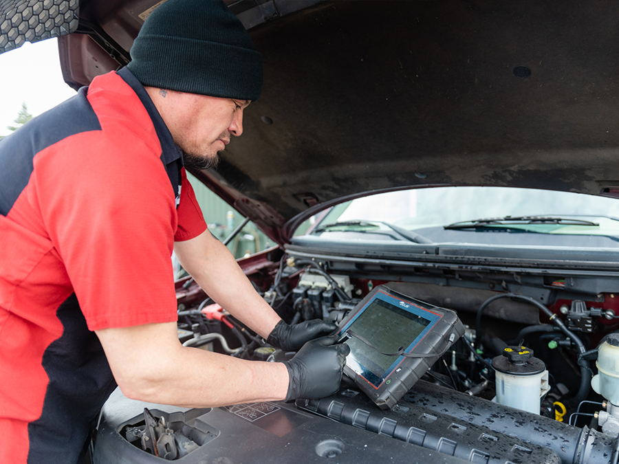 A man in a red shirt is working on a car engine