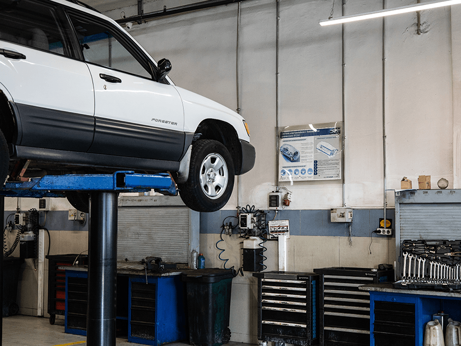 A white car is on a lift in a garage