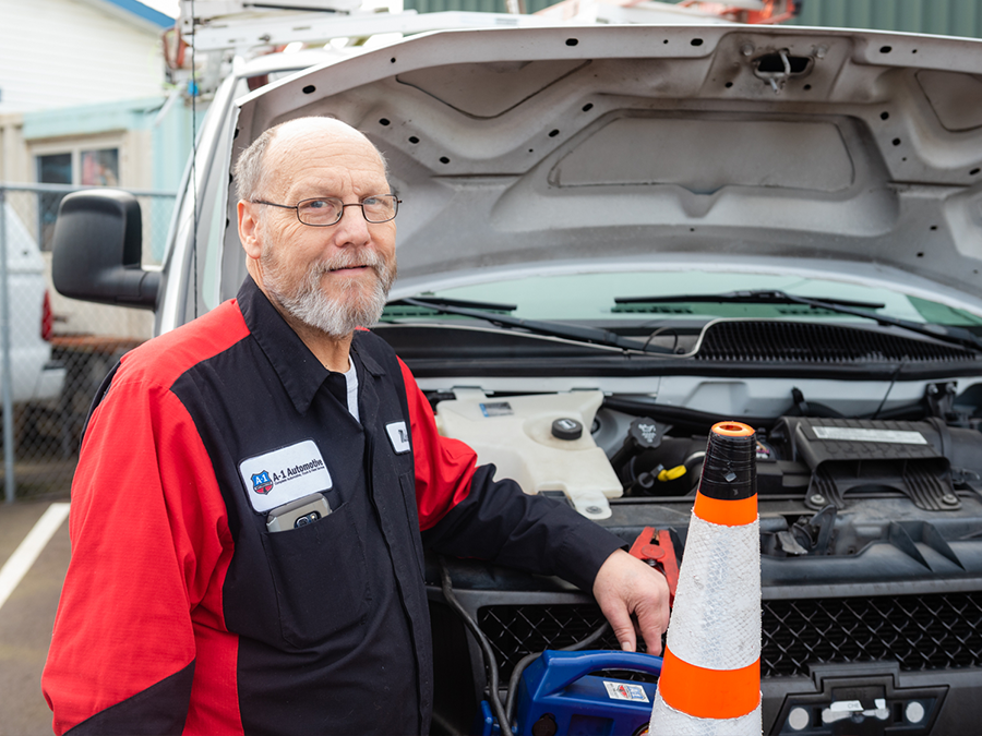 A man standing in front of a silver truck with the hood open