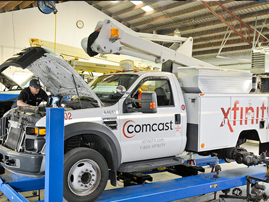 A comcast truck is being worked on in a garage