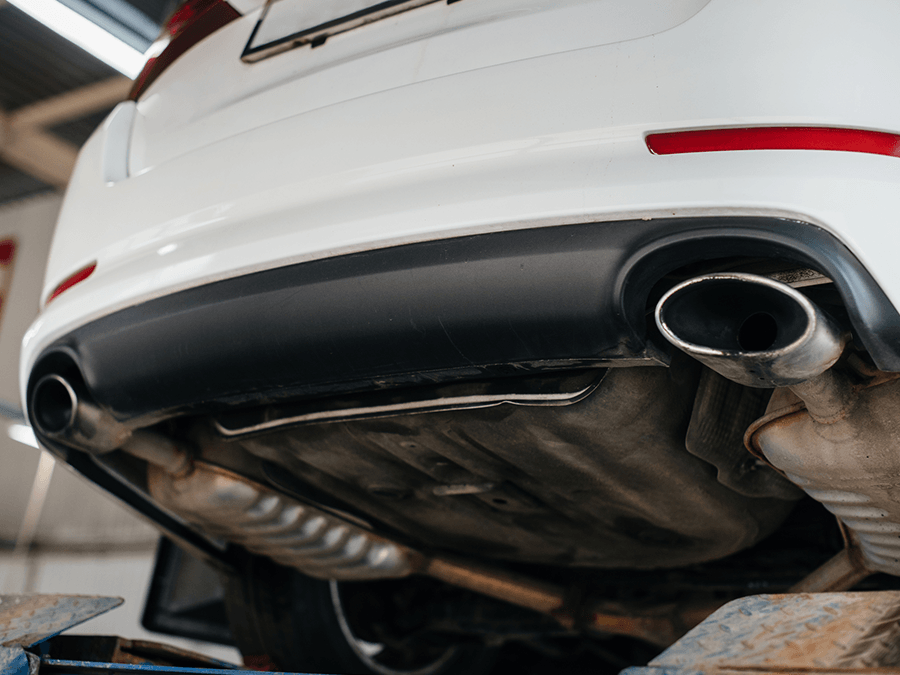 A white car is sitting on a lift in a garage.