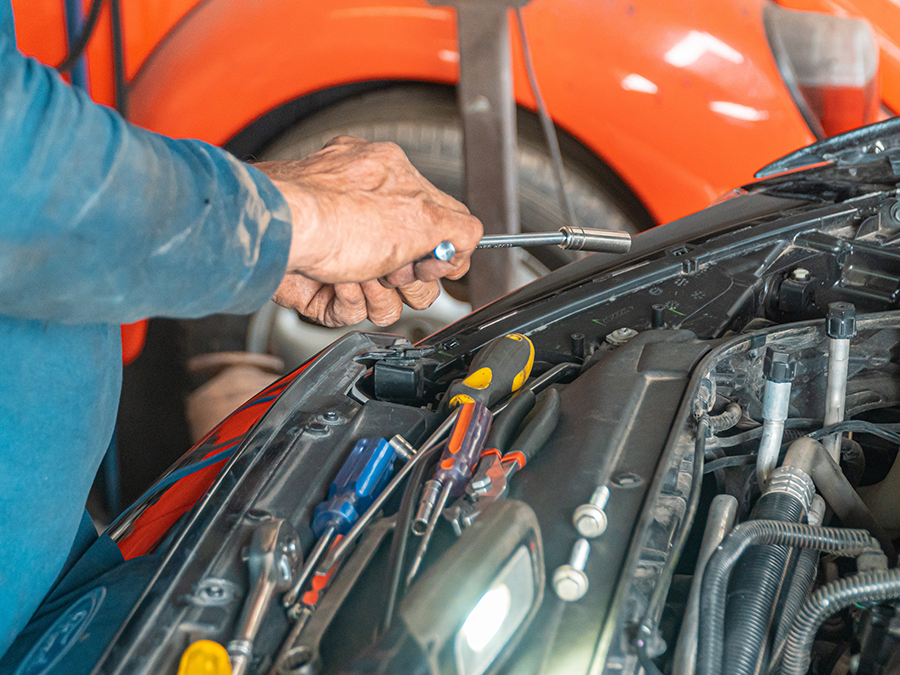A man is working on a car with a screwdriver