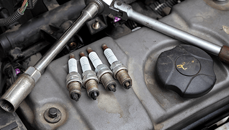 Four spark plugs are sitting on top of a car engine.