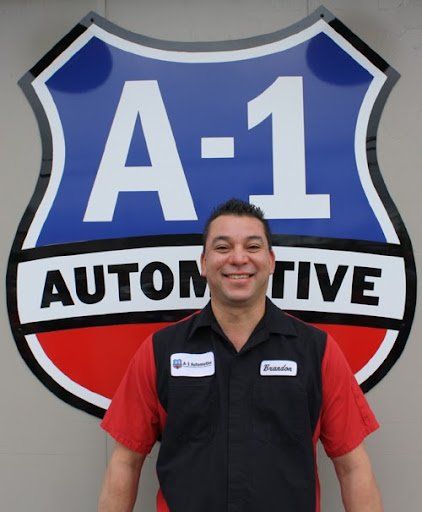 A man stands in front of a sign that says a-1 automotive