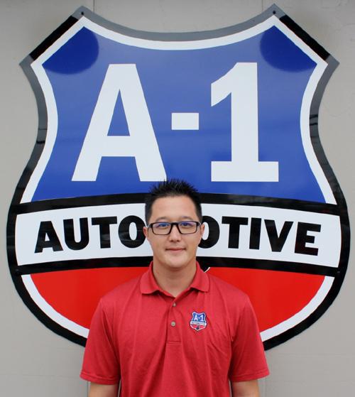 A man stands in front of a sign that says a-1 automotive