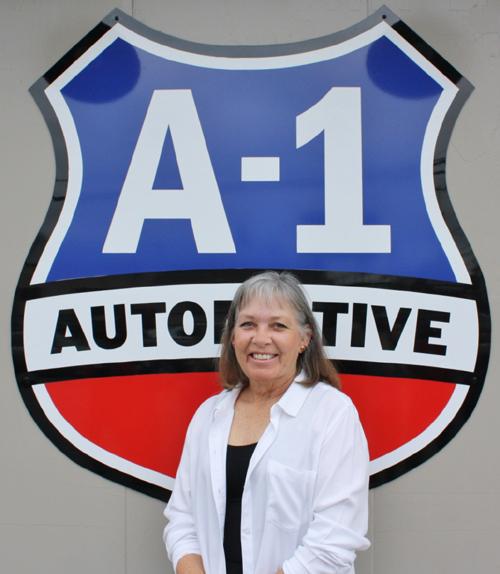 A woman stands in front of a sign that says a-1 automotive