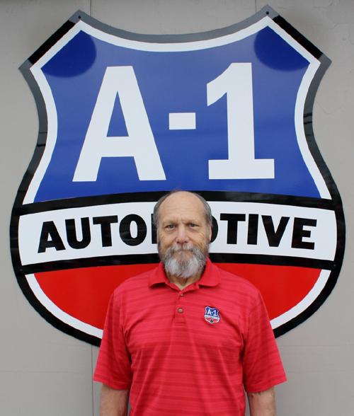 A man stands in front of a sign that says a-1 automotive