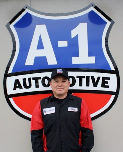 A man stands in front of a sign that says a-1 automotive