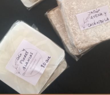 Tres bolsas etiquetadas de granos o arroz sobre una superficie oscura.