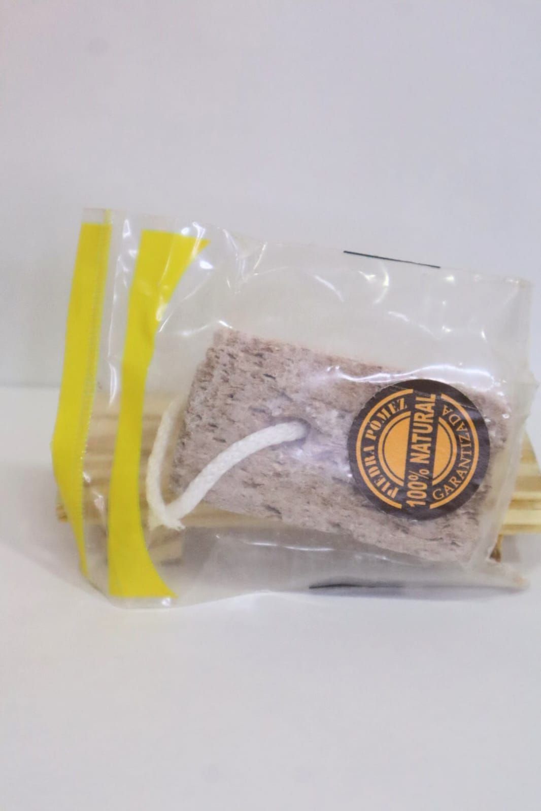 Bolsa de plástico transparente con gránulos grises y rayas amarillas sobre una superficie blanca.