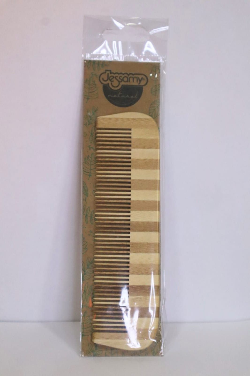 Envase de plástico transparente que contiene un peine a rayas de color tostado y marrón sobre un fondo liso.