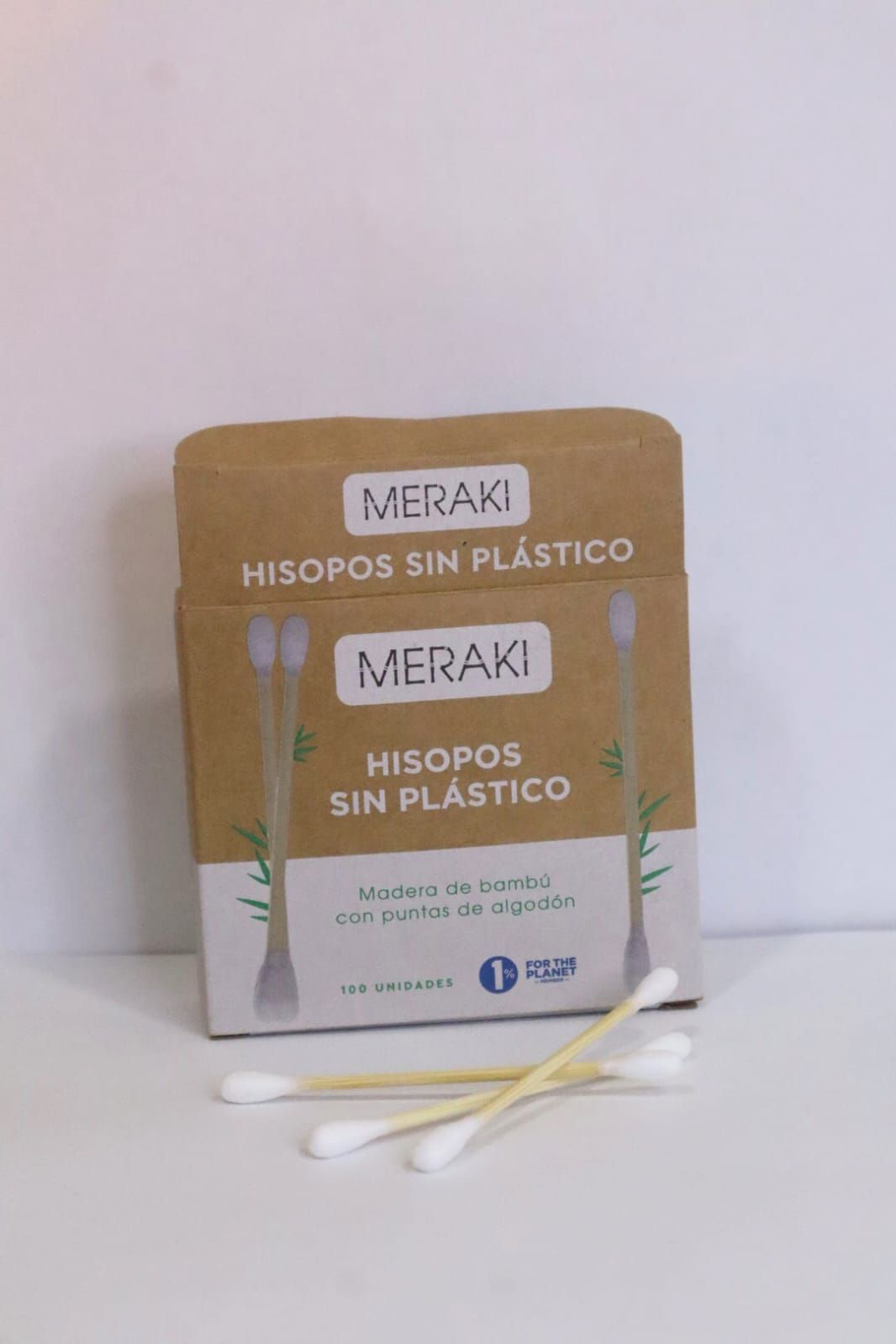 Caja beige de hisopos sin plástico con hisopos blancos sobre una superficie blanca.