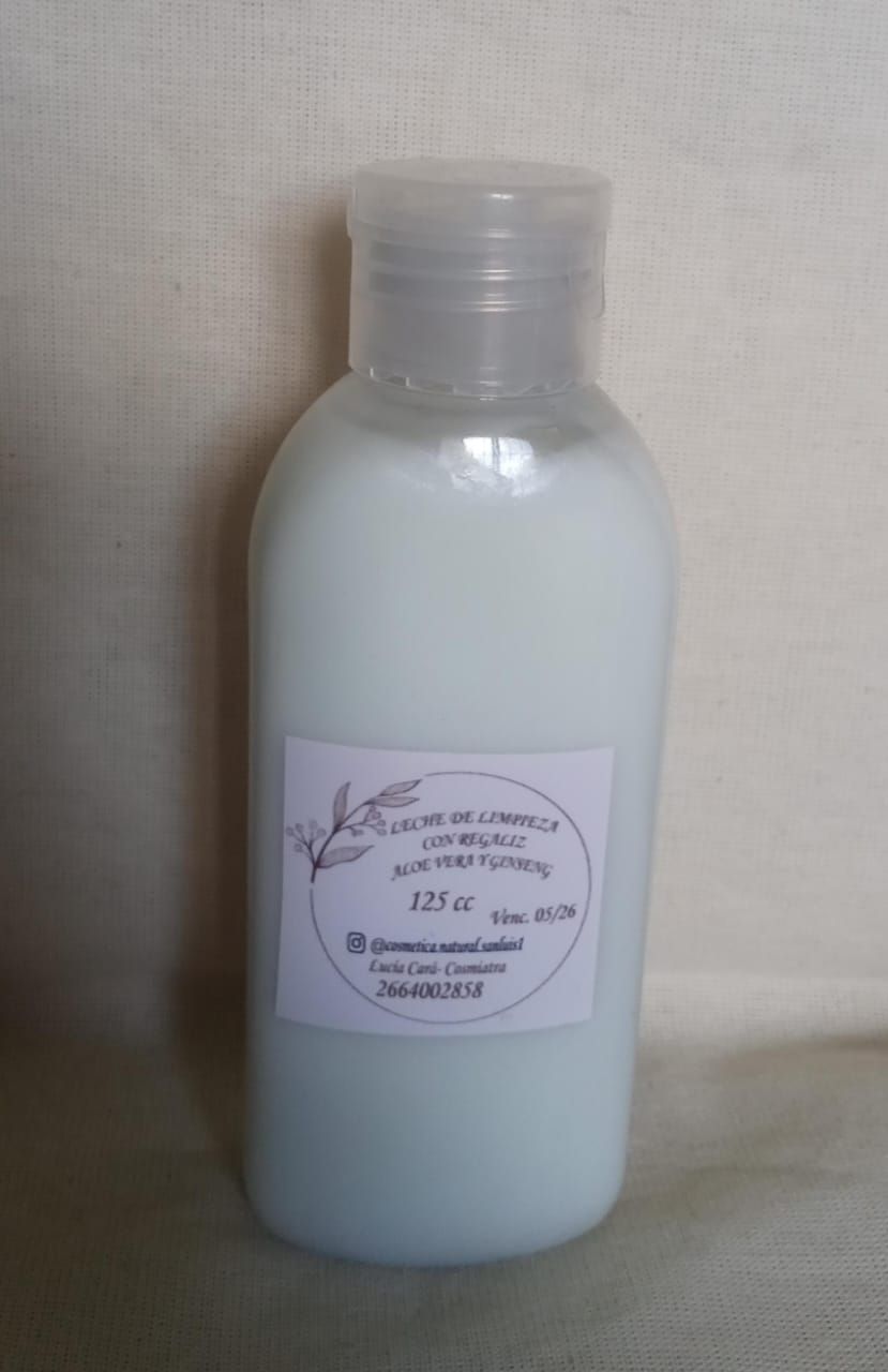 Botella de plástico blanca con una etiqueta rosa pálido, parcialmente llena de líquido lechoso, sobre una superficie beige.