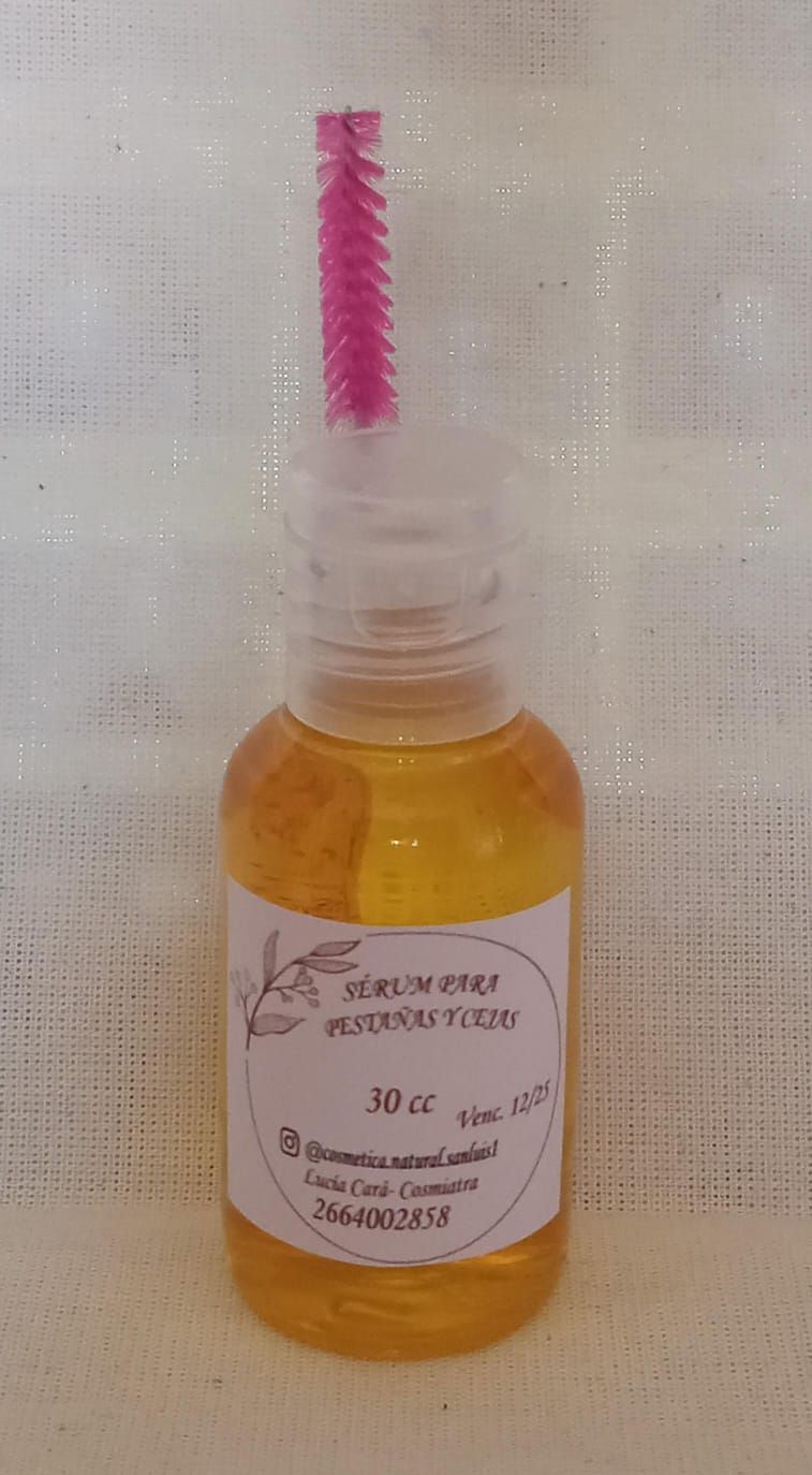 Frasco de líquido color ámbar con tapón de pincel rosa y una pequeña etiqueta blanca.