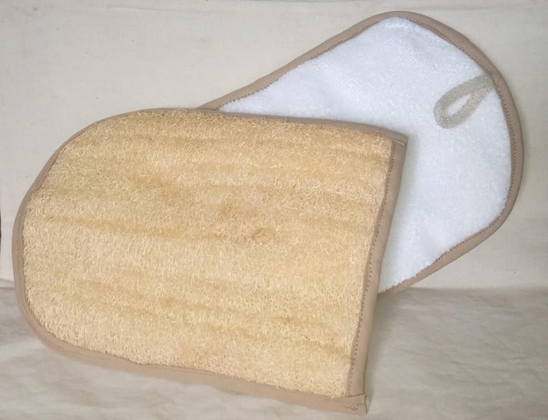 Esponja de baño beige con asa blanca para colgar sobre una superficie clara.