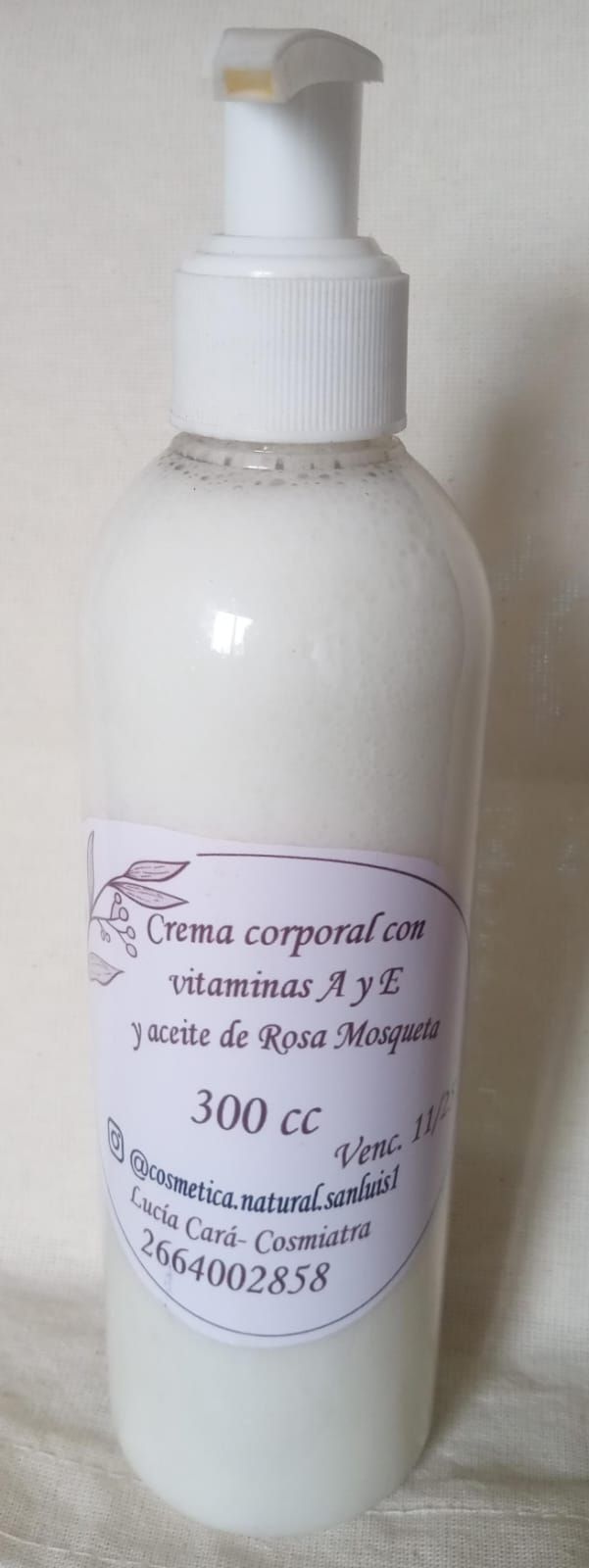 Frasco blanco con dosificador etiquetado como “Crema corporal” sobre un fondo liso.