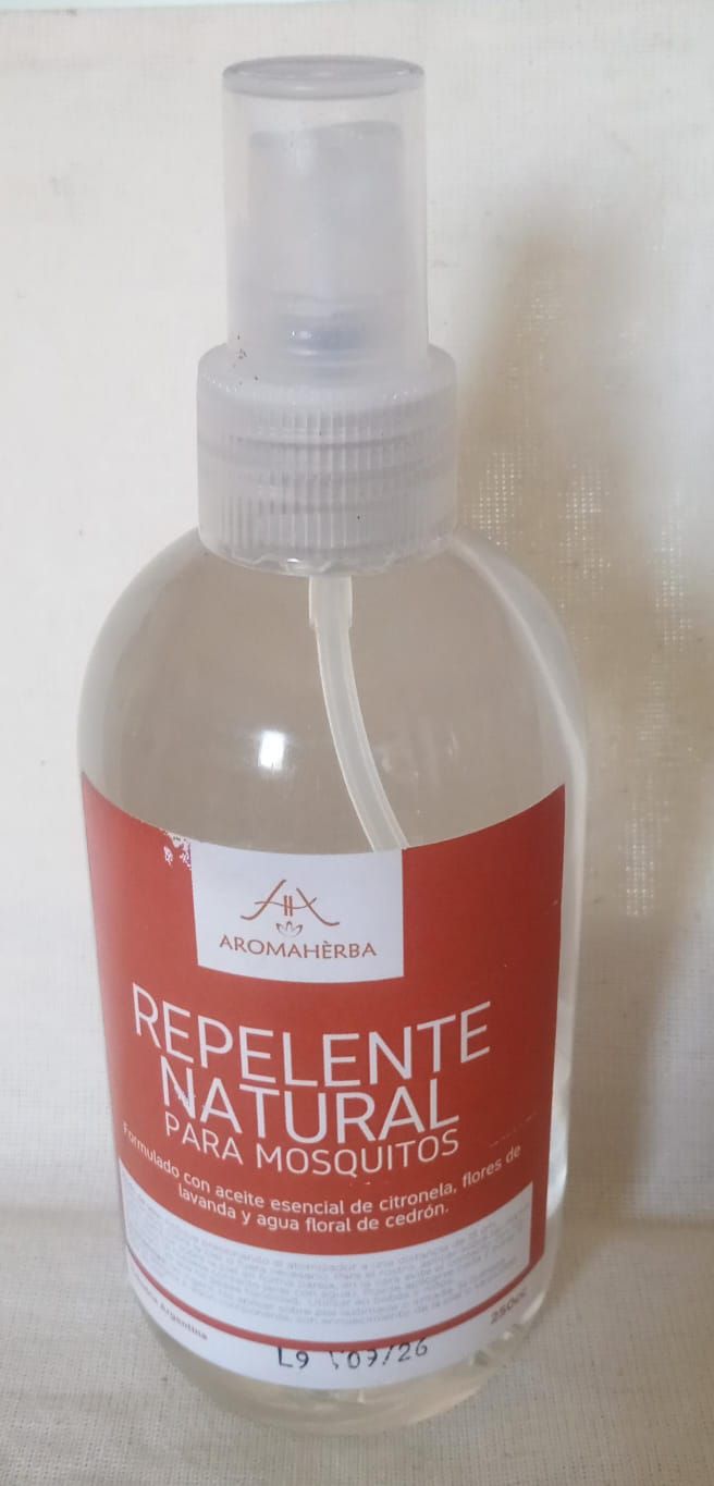 Botella roja en aerosol con la etiqueta “Repelente Natural de Mosquitos” y tapa transparente.