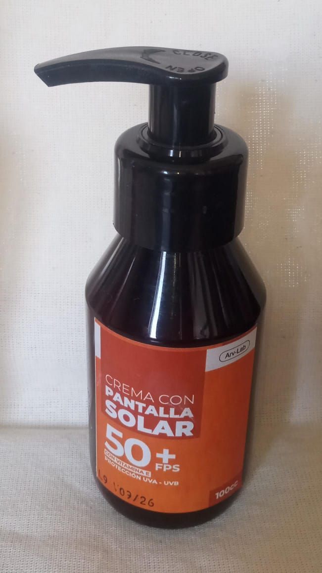 Botella negra con dosificador y etiqueta naranja sobre fondo claro.