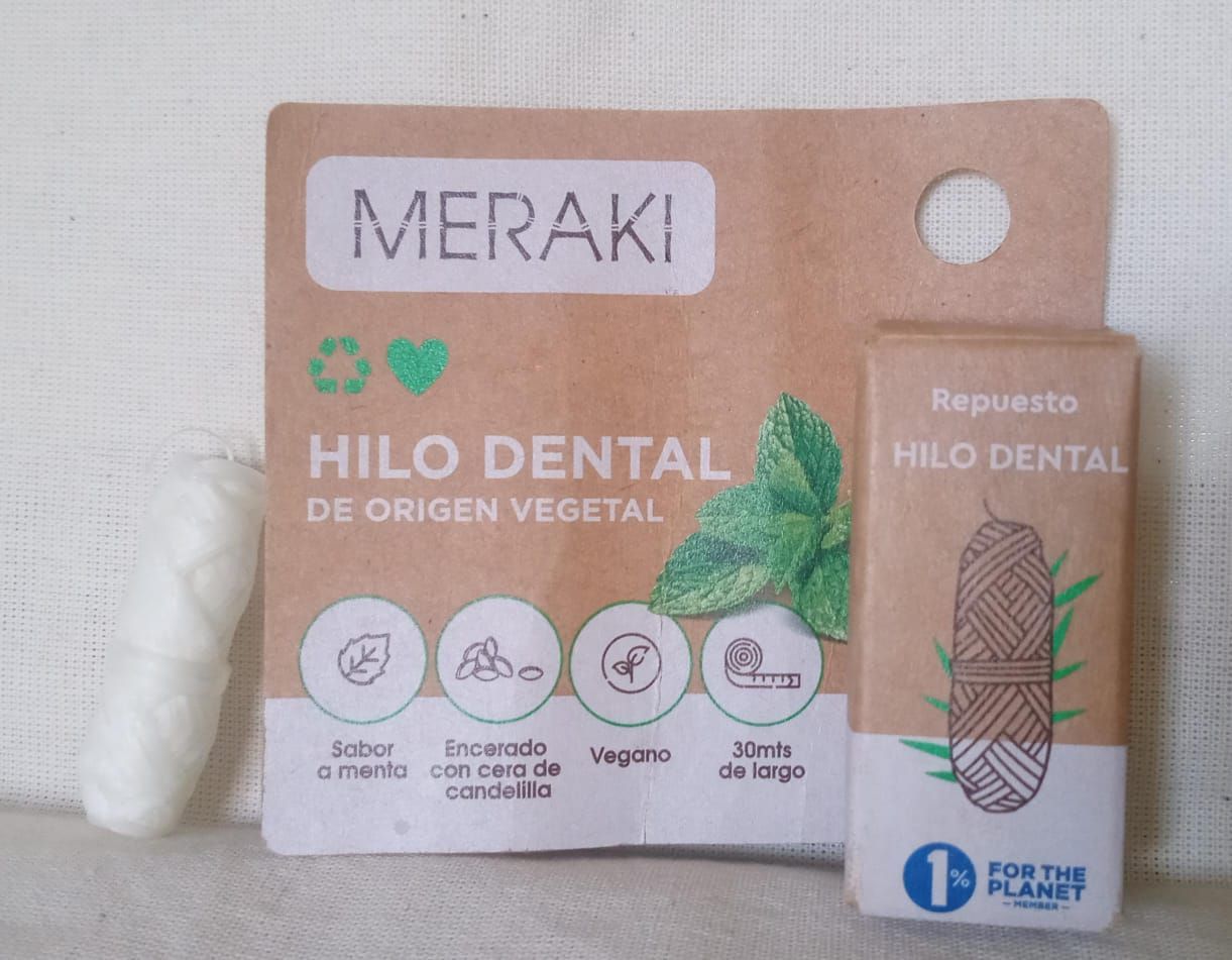 Embalaje del cepillo de dientes de bambú Meraki Hilo Dental y del portacepillos reutilizable sobre una superficie blanca.