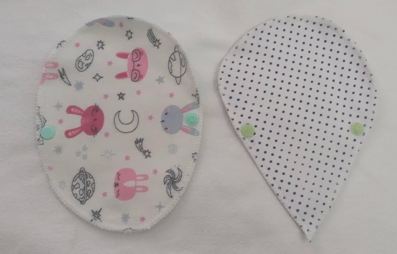 Dos piezas de tela con forma de lágrima, una con estampado de conejitos en tonos pastel y otra con pequeños puntos negros.