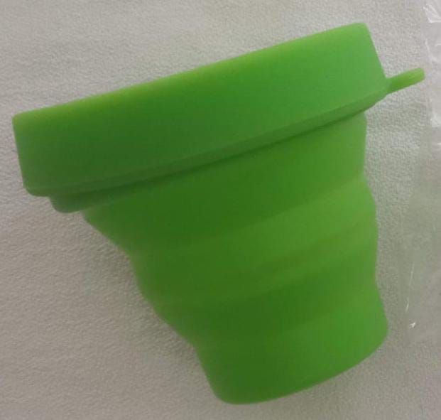 Bol plegable de silicona verde con una pequeña argolla para colgar, mostrado sobre un fondo blanco.