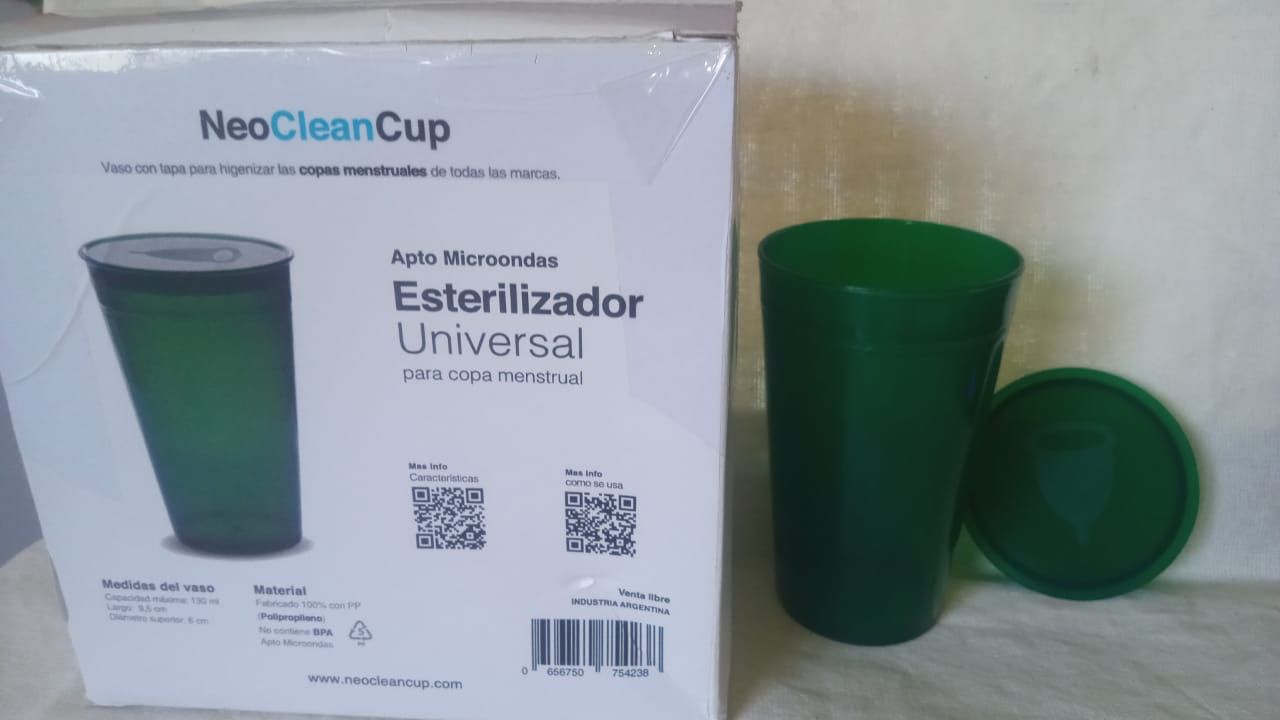 Vaso verde en una caja etiquetada como “NeoCleanCup” y “Esterilizador Universal”, con el vaso y la tapa al lado.