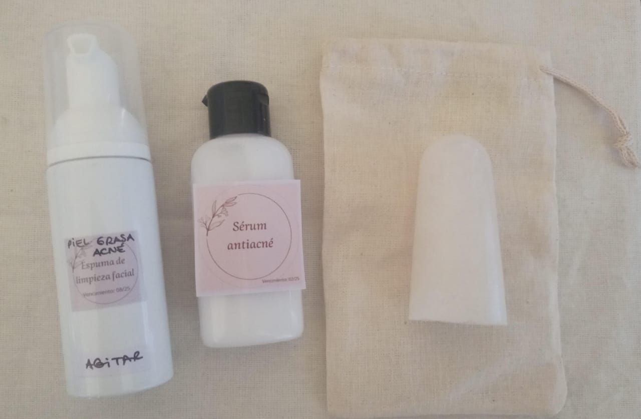 Tres pequeños frascos de cosméticos y una tapa dispuestos sobre una tela de color beige.