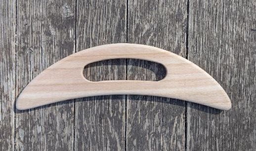 Mango curvo de madera clara con un recorte ovalado, que se muestra sobre una superficie de madera gris.
