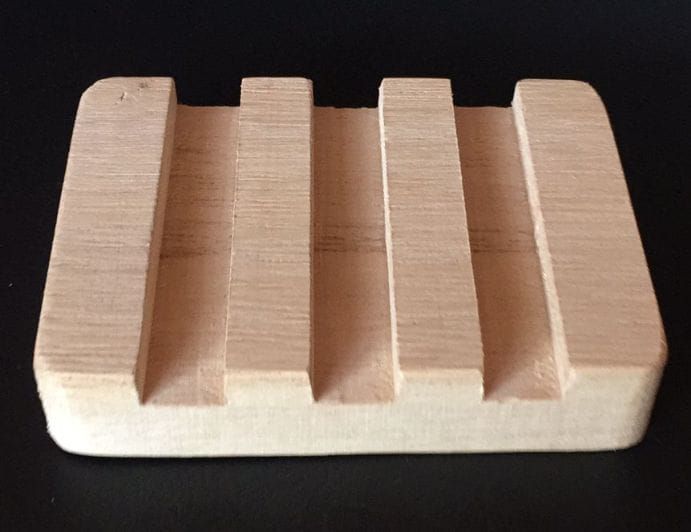 Bloque de madera para rompecabezas con cuatro crestas en relieve sobre un fondo oscuro.