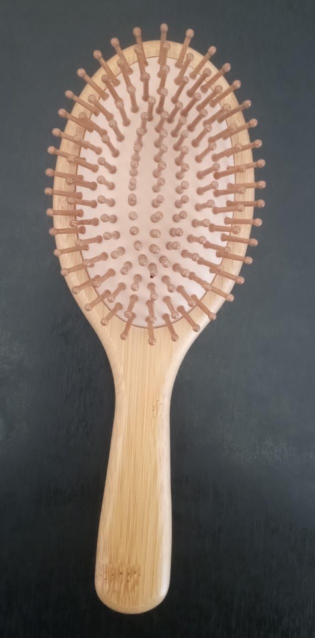 Cepillo de pelo ovalado de madera con cerdas color canela sobre fondo oscuro