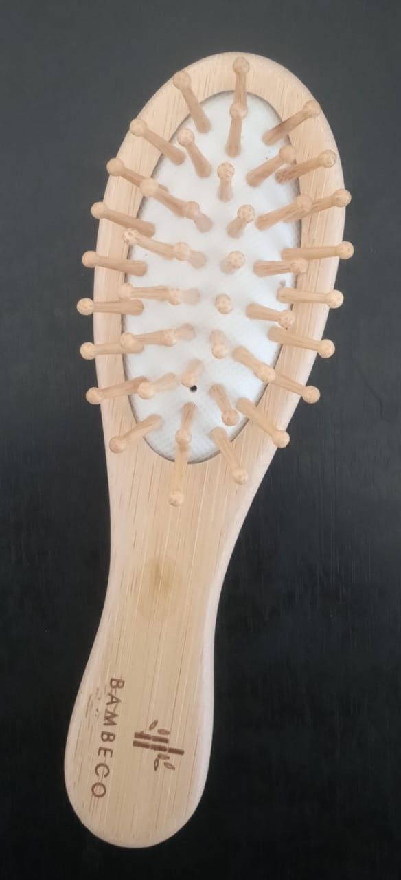 Cepillo de pelo ovalado pequeño de madera con cerdas blancas sobre fondo oscuro