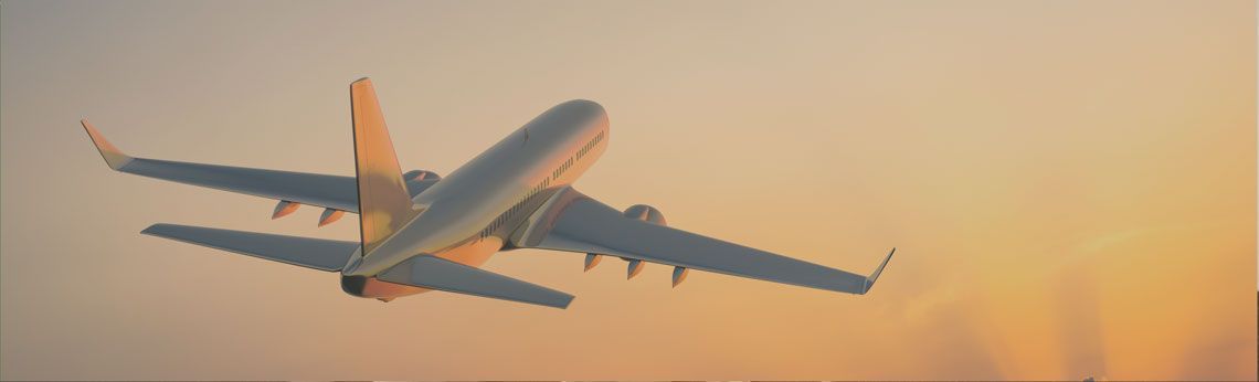 Airplane taking off against a warm orange sky.