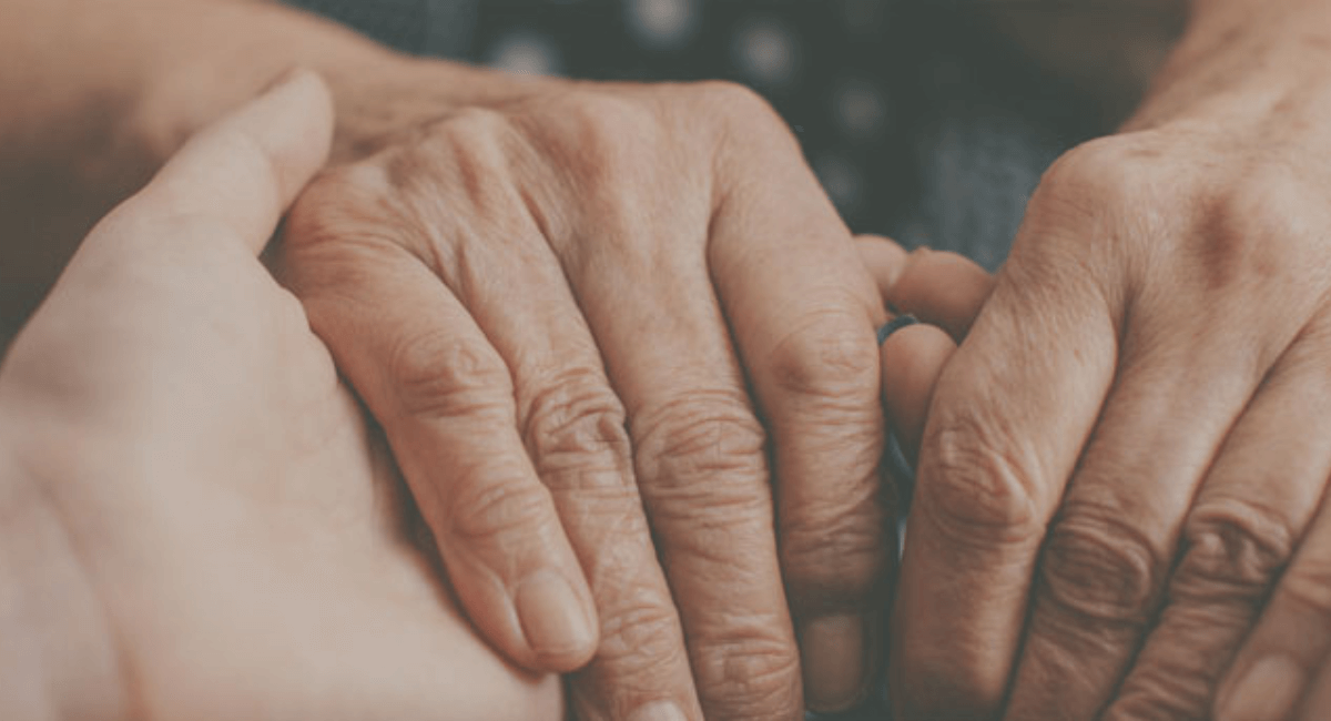 Two pairs of hands clasped together, suggesting support and comfort.