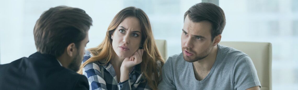 A couple and a person in a black jacket are in a meeting. The woman looks concerned, and the man speaks.