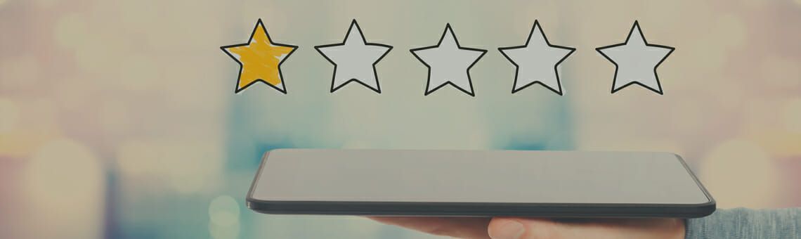 Hand holding a tablet with a one-star rating above.