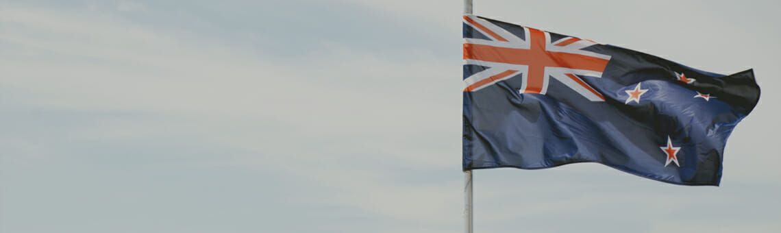 New Zealand flag waving against a cloudy sky.