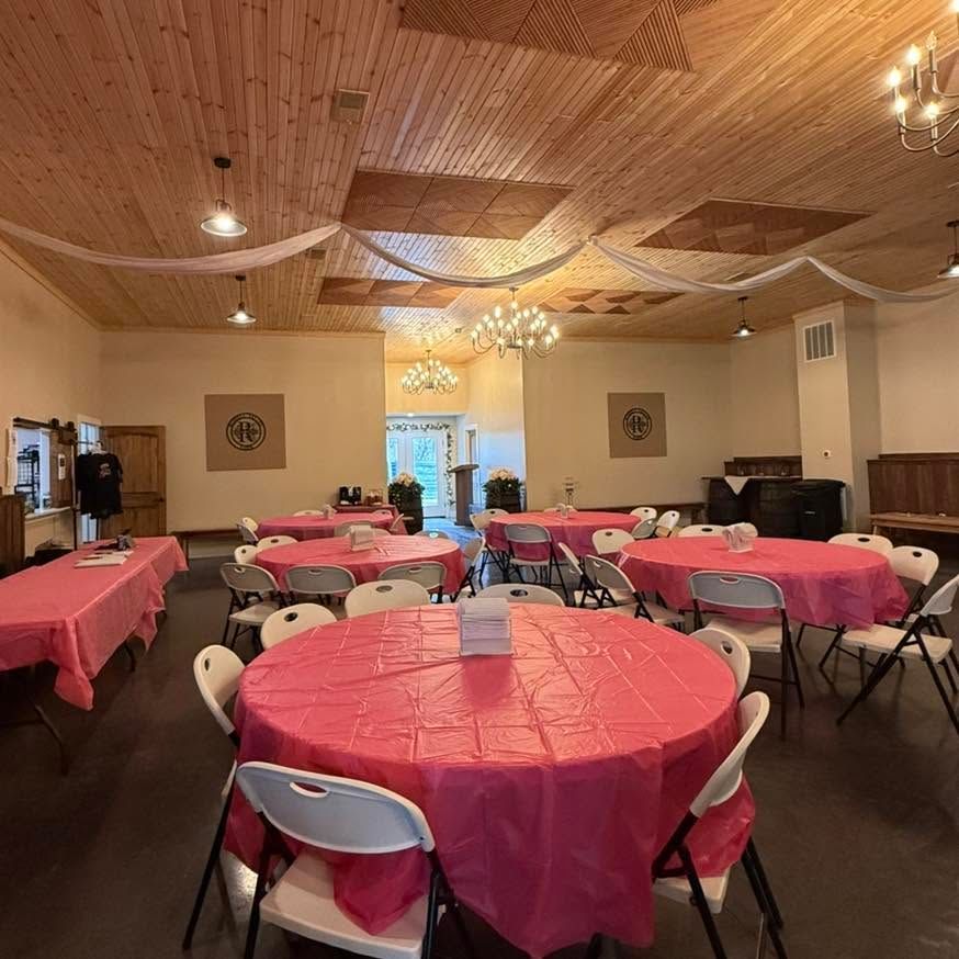 Decorated banquet hall with pink tablecloths and round tables set for an event