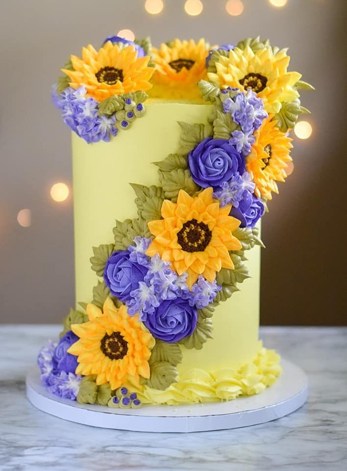 Yellow cake decorated with buttercream sunflowers, purple roses, and hydrangea.