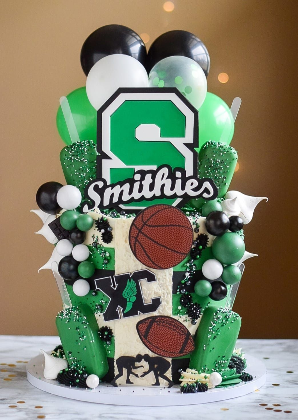Cake decorated with sports and school-themed elements, green and black colors, 